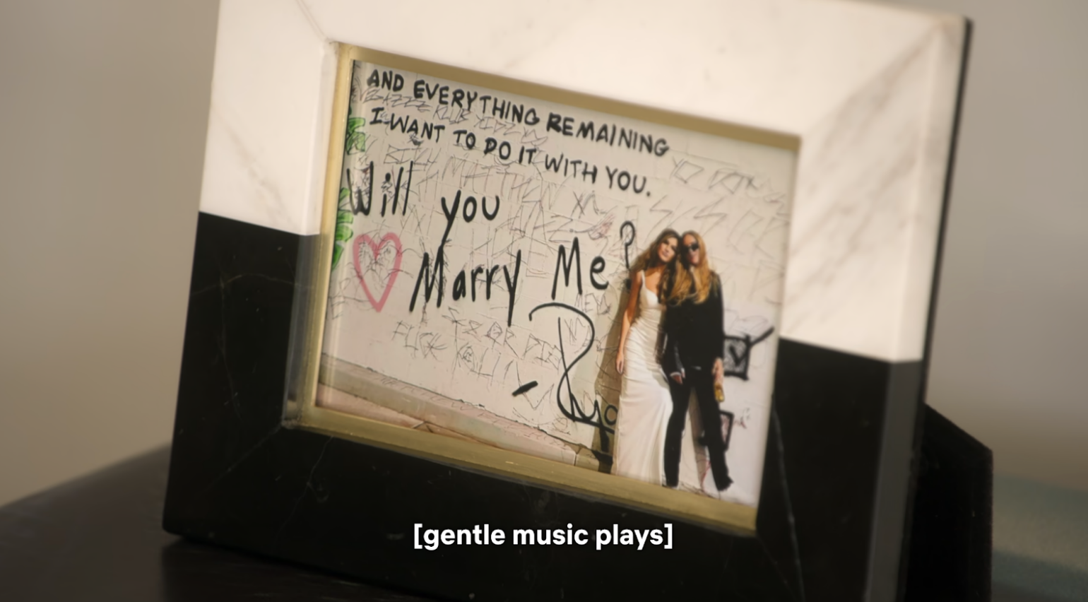 A framed photo of Chrishell Stause and her partner G Flip, with “And everything remaining I want to do it with you. Will you marry me?” handwritten on the photo